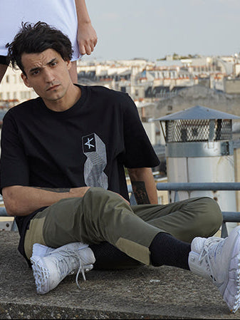 Two people on a rooftop with a cityscape in the background