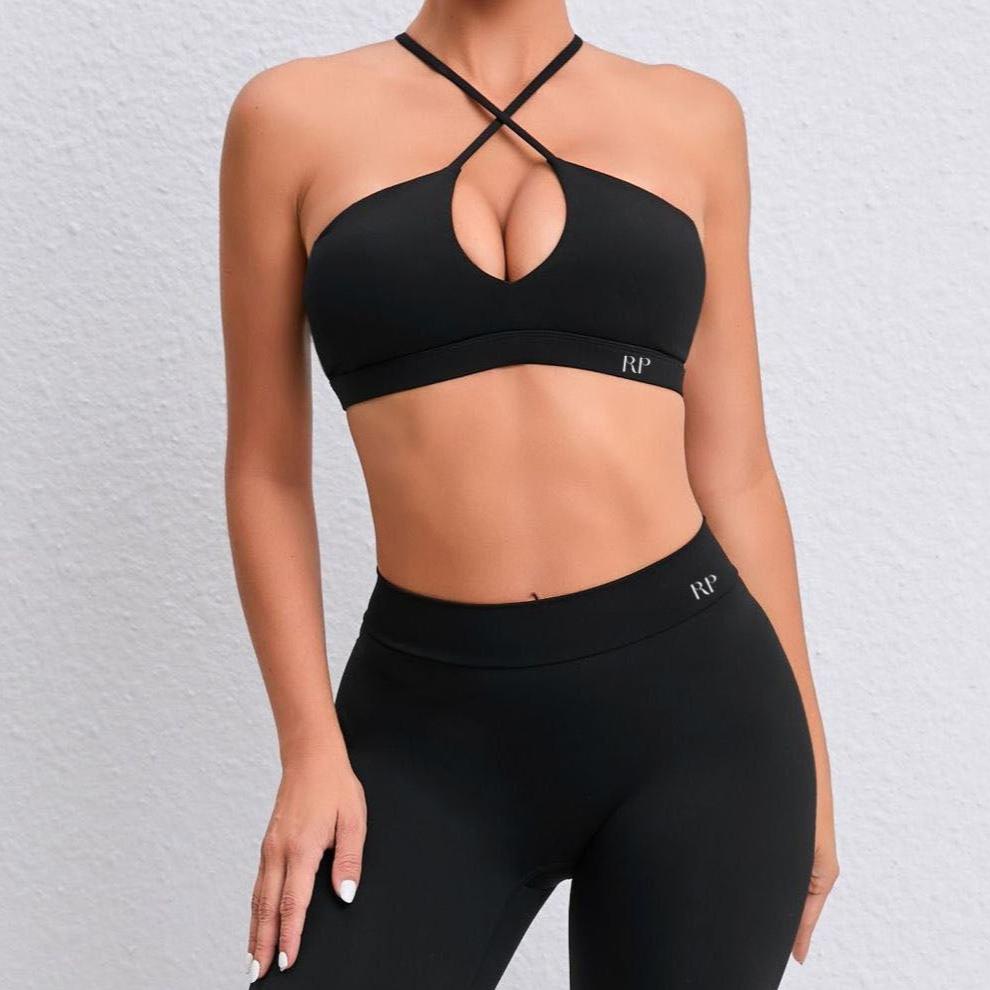 Black sports bra and leggings with criss-cross design on a textured gray background