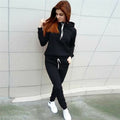 Person wearing a black hoodie and pants with white sneakers against a tiled wall.